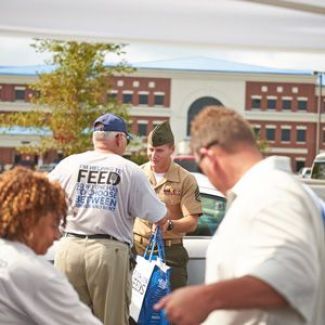 A member of the military volunteers to distribute food.
