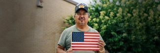 Julio, a veteran, holding an American flag outside a food pantry