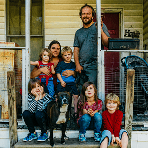 Family with young children sitting on front porch.