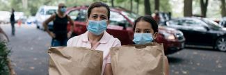 Mother and daughter holding bags of food at mobile pantry