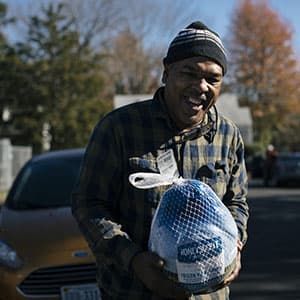 A man smiling and holding a frozen turkey.