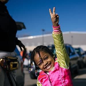 A little girl giving the "peace" sign.