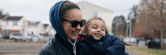 Mother in sunglasses holding son and smiling