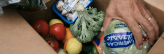 Hand reaching into box containing produce