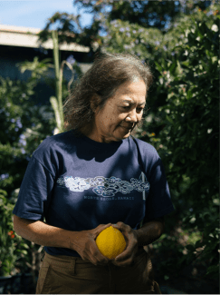 An older woman holding an orange.