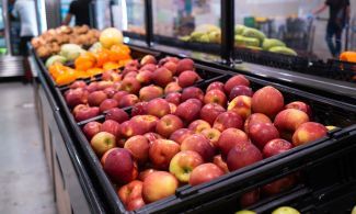 Apples in a bin at a pantry next to other fruit.