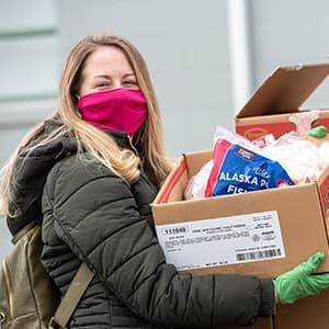 Volunteer holding boxes at drive through food pantry