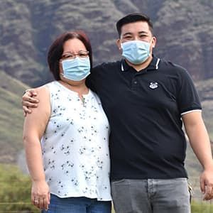 Mother and son hugging outside in field while wearing masks