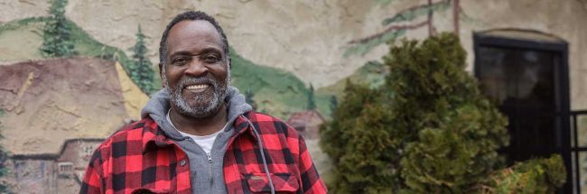 Frederick standing outside of a food bank while smiling.