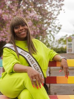 Chelsea sitting on a bench while wearing a pageant sash.