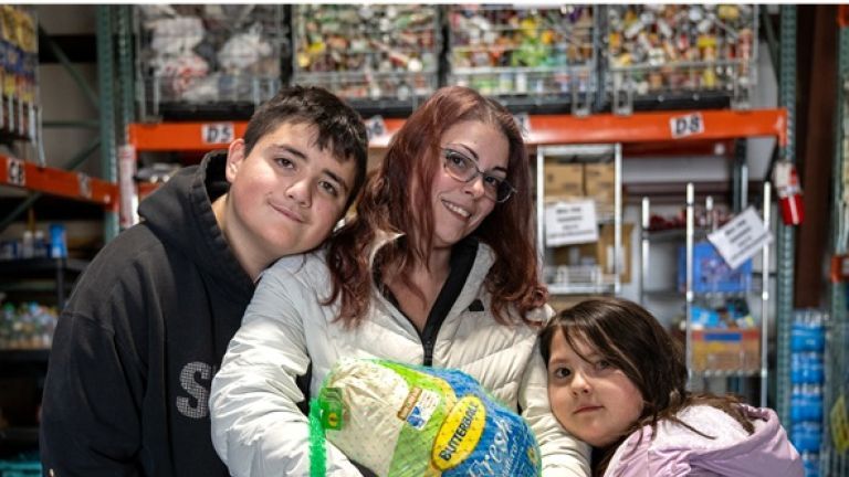 Mother and two children holding a turkey at a food distribution.