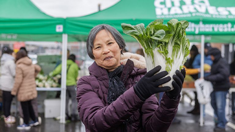 Mu Xiang holding a cabbage at a outdoor pantry.