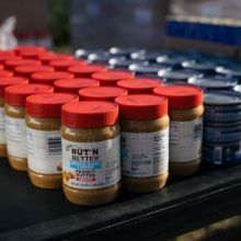 Jars of peanut butter lined up and cans of tuna stacked 