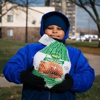 Child wearing winter coat holding packaged turkey
