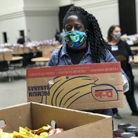 Volunteer wearing face mask and moving boxes at food bank