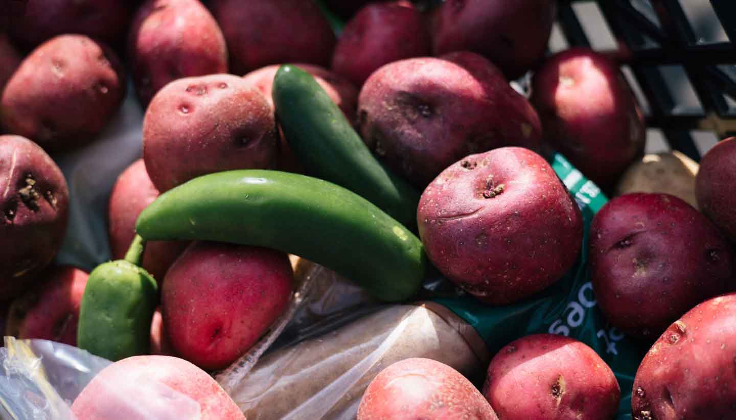 Closeup of produce, mostly red skin potatoes and jalepeno peppers.