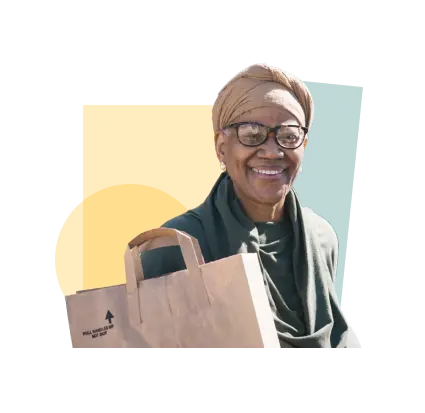 A smiling older woman with a turban holding groceries