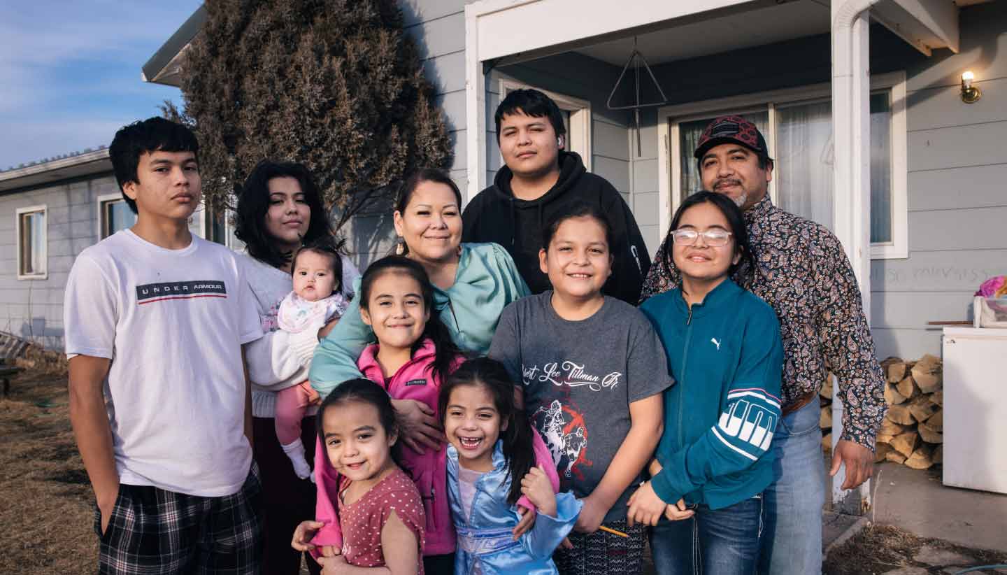 A multigenerational family portrait in front of a well-kept, modest home.